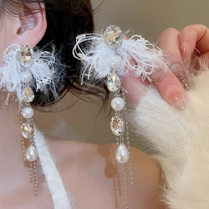 Detail of long tassel earrings featuring white feathers, crystals, and silver chains