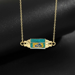 Detailed macro view of a gold hexagonal rotating pendant with multi-colored enamel and YOU text