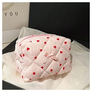 Pink quilted makeup bag with red hearts and bow detail in an elegant gift box