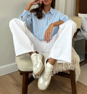 Gros plan de baskets en cuir et daim à semelles en gomme avec chemise rayée et pantalon blanc