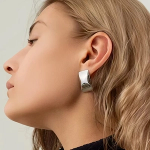 Close-up of model wearing polished silver-tone rectangular earrings in stainless steel