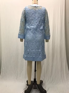 Détail d'un cardigan en dentelle crochetée bleu clair montrant le dos et les motifs floraux