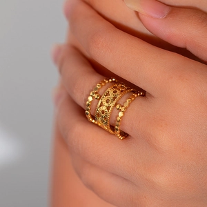 Detailed macro view of gold plated sunflower cut-out ring with beaded bands on a finger