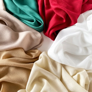 Close-up of lightweight linen cotton scarves in vibrant green, red, and beige textures