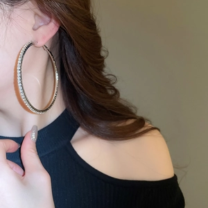 Close-up of a large silver hoop earring with pavé rhinestones on a female model