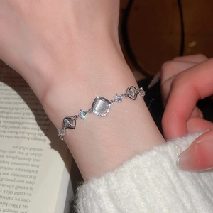 Close-up of zircon flower bracelet with cat eye stone worn against a white sweater