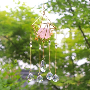 Detail of pink crystal suncatcher with golden geometric frame and hanging crystal prisms