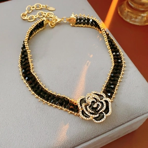 Detail of a rose pendant necklace with black petals and sparkly crystals on velvet