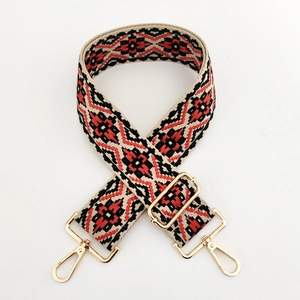 Close-up of ethnic jacquard shoulder strap with red geometric patterns and gold metal hooks