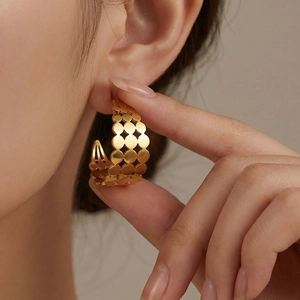 Élégantes boucles d'oreilles dorées forme C avec motif géométrique ajouré sur mannequin