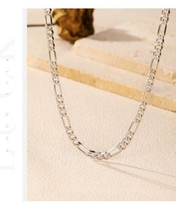 Macro shot of silver Figaro chain necklace with polished links on a textured stone base