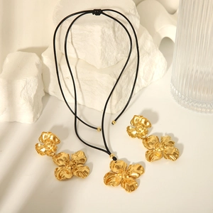 Elegant 18K gold stainless steel flower necklace and earrings set on white stone background