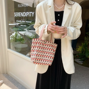 Close-up of corduroy tote bag with red floral pattern and pink straps on a female model