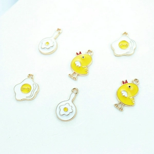 Detail view of cartoon chicken and fried egg enamel charms for DIY jewelry making