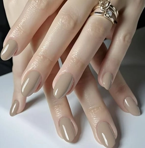 Detalle macro de uñas postizas brillantes color albaricoque nude con forma ovalada y anillo