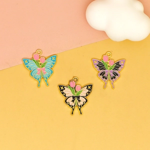 Three enamel butterfly tulip pendants with gold frames in blue, purple, and beige tones