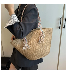 Dettaglio della borsa in paglia intrecciata con manici colorati e nappe vivaci