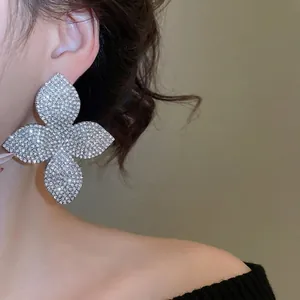 Orecchini a lobo a fiore oversize con pavé di cristalli indossati da una modella