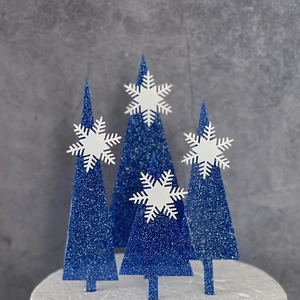 Set of four blue glitter Christmas tree cake toppers with white snowflake details