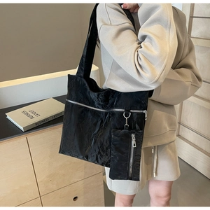 Detail of black pleated tote bag with zipper decor and detachable matching mini pouch