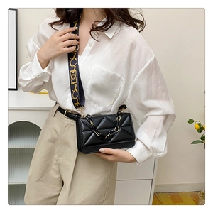 Detail of black quilted crossbody bag with textured leather and wide jacquard strap