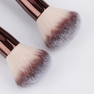 Detailed macro of fluffy tri-color gradient bristles and rose gold ferrule on makeup brush
