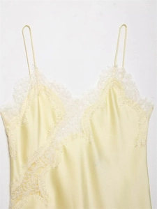 Detailed close-up of light yellow satin camisole featuring delicate white lace trim edges