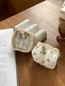 Quilted floral fabric pouches for data cables and earbuds on a rustic wooden desk