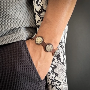 Vintage brown leather bracelet featuring star and gear metal studs on a wrist