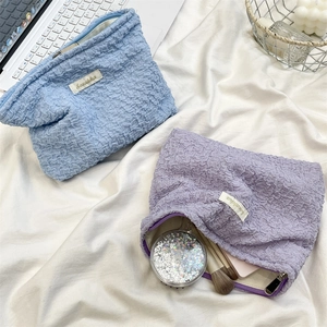 Close-up of bubble texture makeup pouches in blue and purple showing zipper and fabric details
