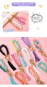 Detail of colorful resin chain keychains with gold clasps and matching tassels on pink backdrop
