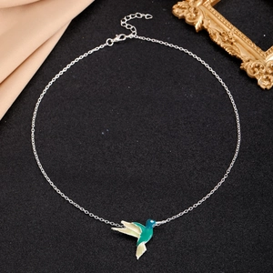 Close-up of elegant silver hummingbird necklace with green and beige enamel pendant detail