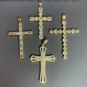 Macro shot of four gold-plated cross pendants with cubic zirconia on gray leather
