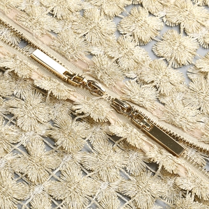 Detailed macro view of champagne gold floral embroidery and metallic zipper on garment
