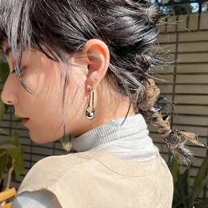 Polished gold U-shaped drop earrings shown on a model in a natural outdoor setting