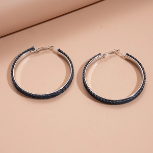 Macro detail of large hoop earrings wrapped in textured dark blue denim fabric