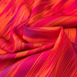 Detail von leuchtend orangefarbenem und magentarotem Stoff mit eleganten Falten