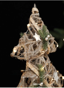 Macro shot of rattan Christmas star topper with warm LED lights and artificial snow