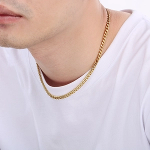 Close-up of a polished gold Cuban link chain necklace worn on a white t-shirt