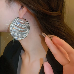 Close-up of sparkling full-rhinestone geometric hoop earrings worn by a model