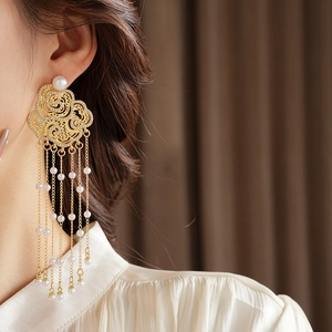 Close-up of golden flower tassel earrings with rhinestones and pearls on a model