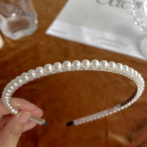 Detail shot of a minimalist white pearl headband featuring a single row of elegant pearls