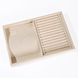 Beige velvet jewelry display tray with ring slots and necklace hooks on white background