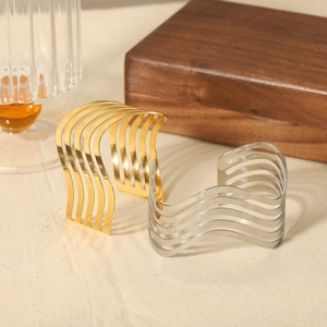 Minimalistische hohle Wellenarmreifen in Gold und Silber auf Holzuntergrund