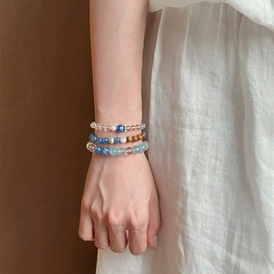 Nahaufnahme von Perlenarmbändern aus Bergkristall und blauem Kyanit am Handgelenk der Frau