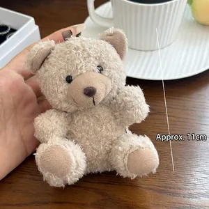 Close-up of a 11cm light brown plush teddy bear keychain held by hand for scale