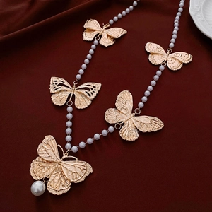 Macro detail of golden metal butterflies and faux pearls on a vintage-style necklace