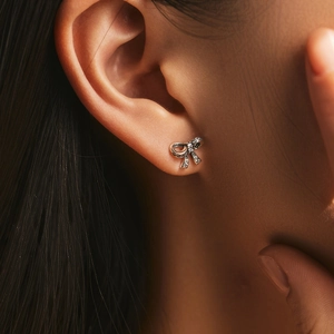 Elegant s925 silver bow stud earrings with sparkling crystals worn by a model