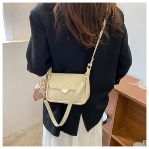Detail of cream crossbody bag with round magnetic clasp and decorative floral silk scarf