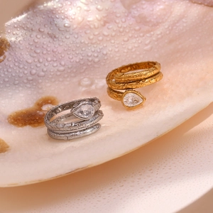 Close-up of gold and silver snake rings with pear-cut zircon on a wet shell base